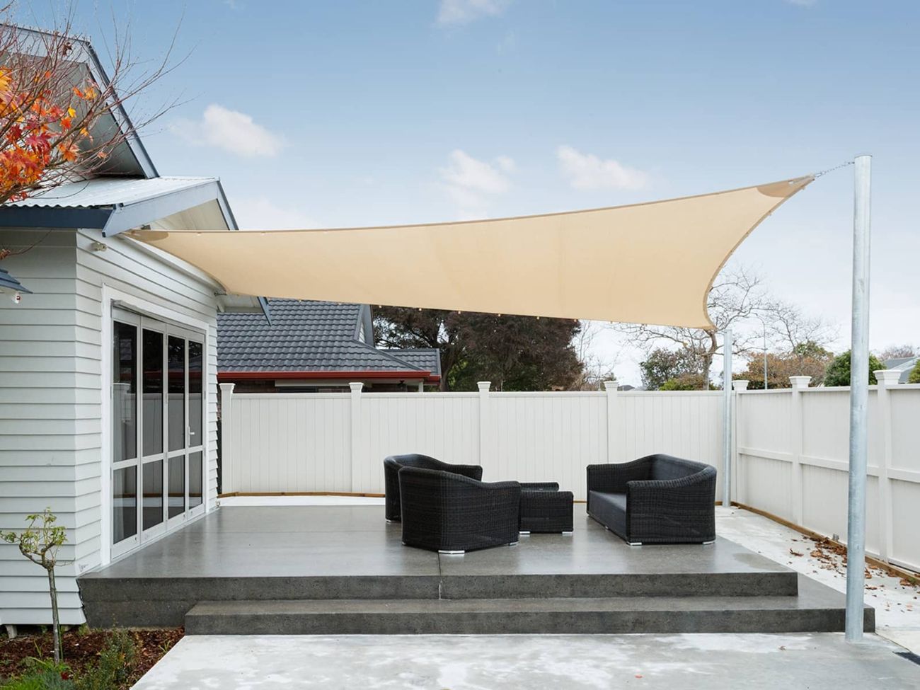 Cream shade sail with steel poles protecting a beautiful concrete outdoor area
